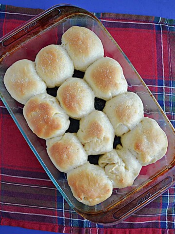 A baking dish with 12 golden brown rolls in it.