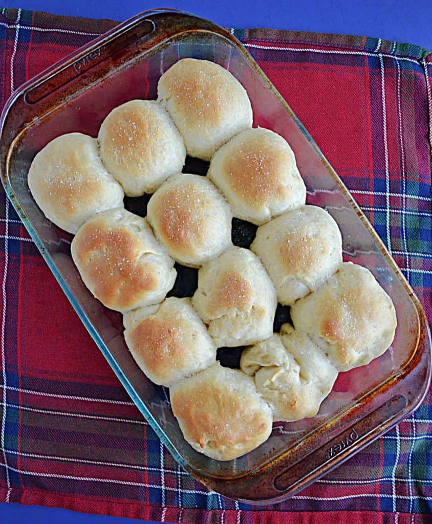A baking dish with 12 golden brown rolls in it. 