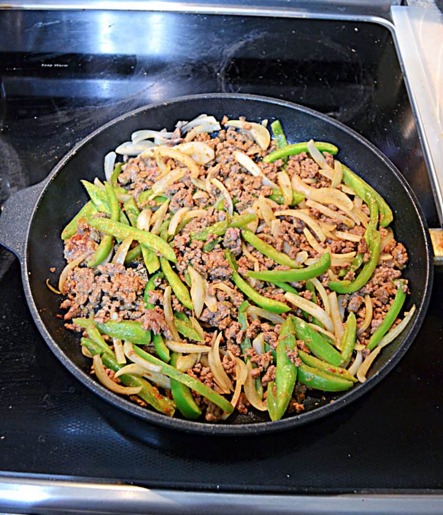 A skillet full of ground beef, peppers, and onions.