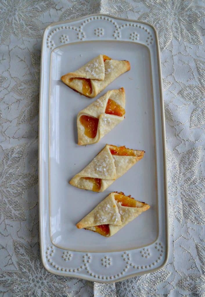 A platter with four Polish Cream Cheese Cookies filled with apricot jam. 