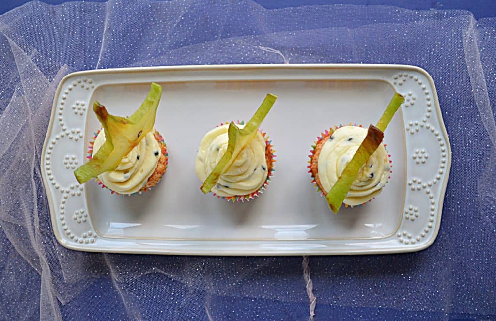 A plate with 3 Tropical Cupcakes topped with a slice of star fruit.