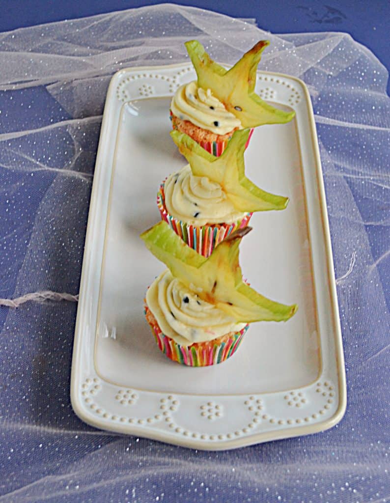 A white platter with 3 Tropical Cupcakes topped with a slice of star fruit.