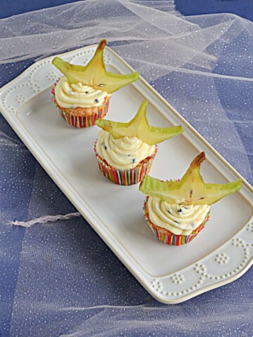 A white platter with 3 Tropical Cupcakes topped with a slice of star fruit.