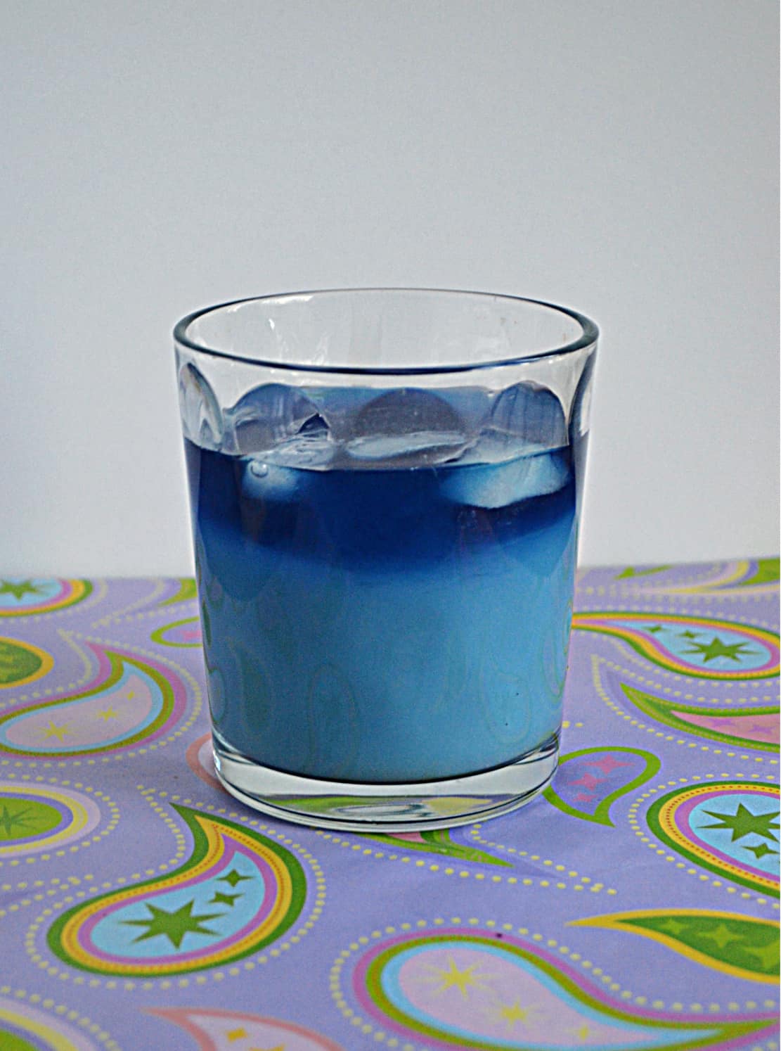 A glass of Butterfly Pea Flower Iced Tea Latte (light blue on the bottom, dark blue on the top)