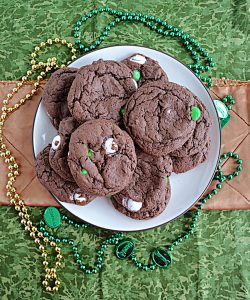 A plate piled high with chocolate cake mix cookies surrounded by green and gold beaded necklaces.