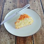A plate with a giant Zucchini Cheddar scones with a knife on the plate.