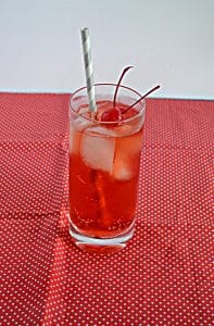 A glass filled with a Cherry Vanilla Bourbon Fizz with 2 cherries and a straw.