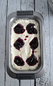 A loaf pan filled with ice cream and dolloped with blueberry sauce.