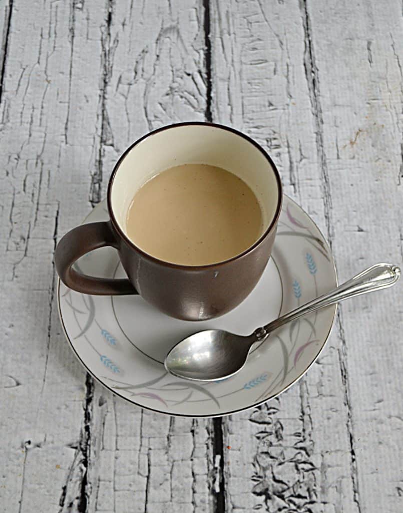 A cup of Royal Milk Tea on a saucer with a spoon on the saucer.