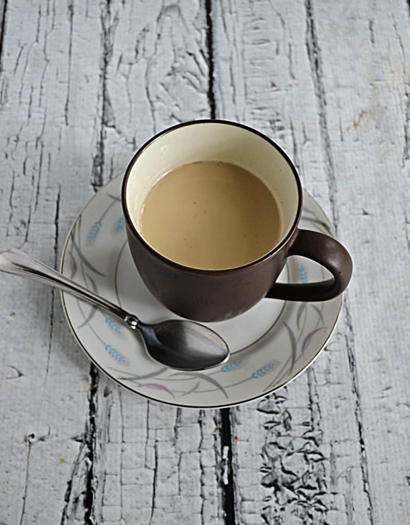 A cup of Royal Milk Tea on a saucer with a spoon next to it. 