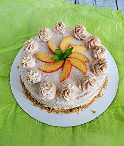 A brown sugar cake with peach vanill frosting topped off with peach slices and fresh mint.