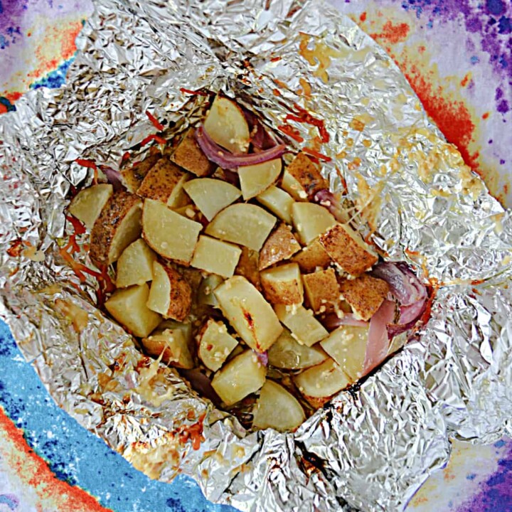 A foil packet filled with cooked potatoes, onions, and cheese.