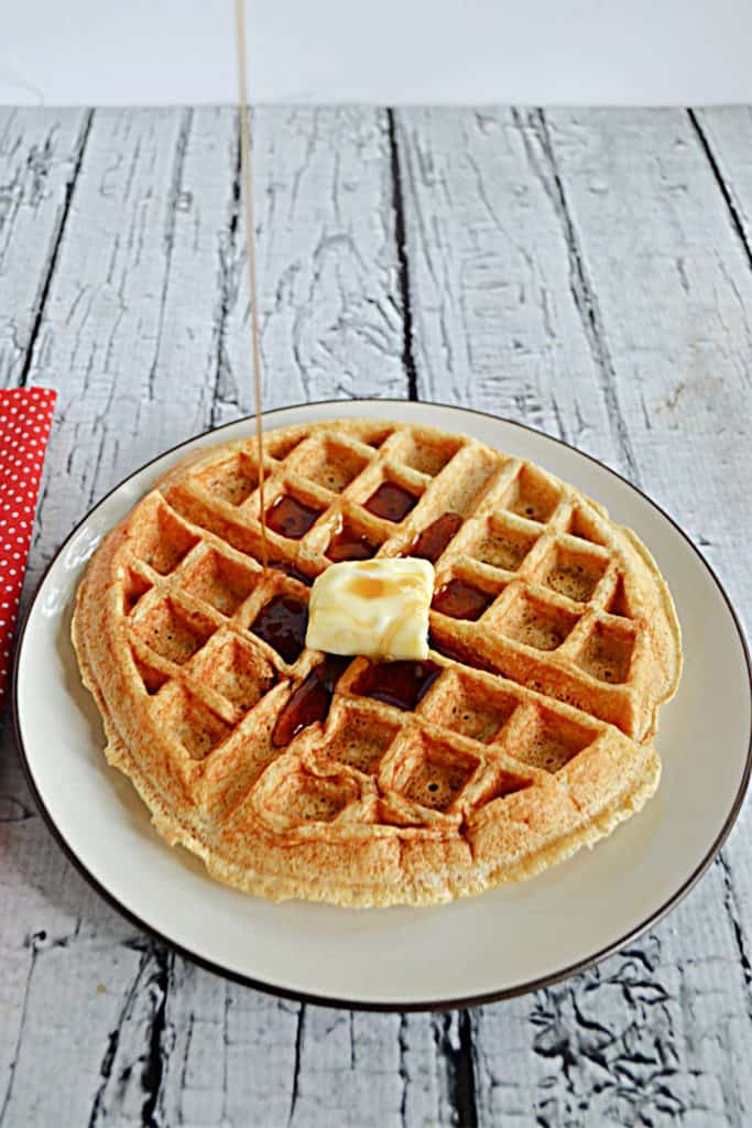 A plate with a large Apple Spice Cake Mix Waffle on it with a pat of butter on top.