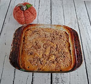 A pan of Pumpkin Spice Coffee Cake with a pumpkin behind it.