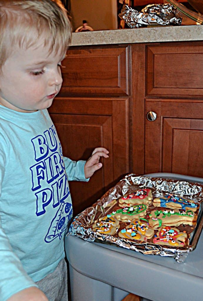 A toddler looking at a sheet of decorated cookies.