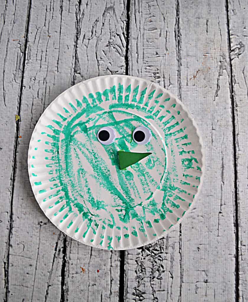 A paper plate witch colored green with google eyes and a nose.
