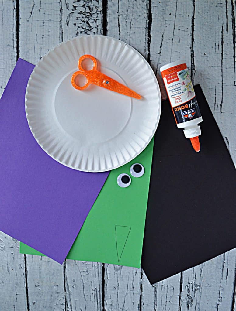 Purple, green, and black construction paper, a paper plate, scissors, google eyes, and glue.