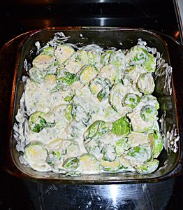 A baking dish with Brussels Sprouts mixed with a cream cheese mixture.