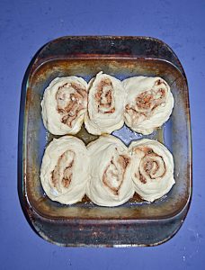 A baking dish with six unbaked cinnamon rolls in it.