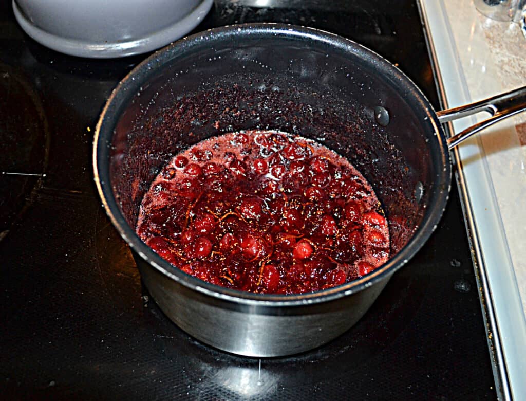 A pan filled with cranberries with bourbon and oranges.