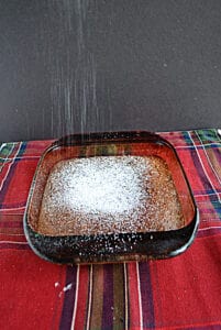 A pan of Gingerbread Snack Cake with powdered sugar coming down on top of it.