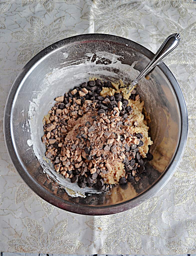 A bowl of cookie dough with toffee chips and chocolate chips on top. 