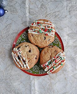 A plate with three cookies on it drizzled with white chocolate and sprinkles.