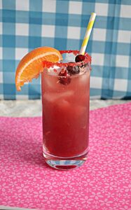 A glass of Cranberry Orange Mocktail with an orange wedge on the glass and three cranberries in the glass.