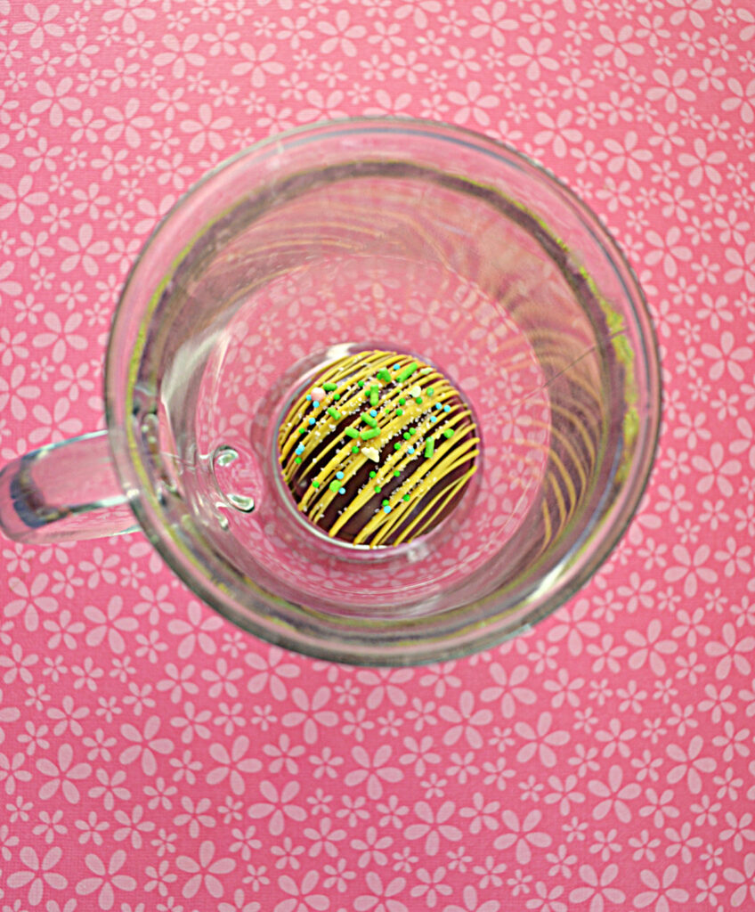 An overhead view of a mug with an Easter Hot Cocoa Bombs in it.