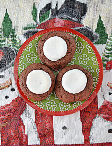 A plate with three hot cocoa cookies each topped with a marshmallow.