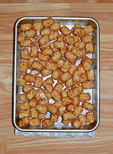 A baking sheet with tater tots on it.