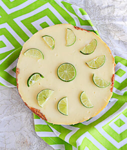 A cheesecake with a lime in the middle and lime wedges around the edges.