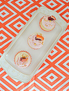 A platter with three Blood Orange Cupcakes each with a wedge of orange on top.