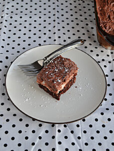 A plate with a marshmallow brownie covered in chocolate frosting and a fork on the plate.