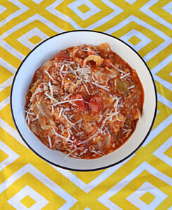 A bowl of stuffed cabbage soup with cheese on top.