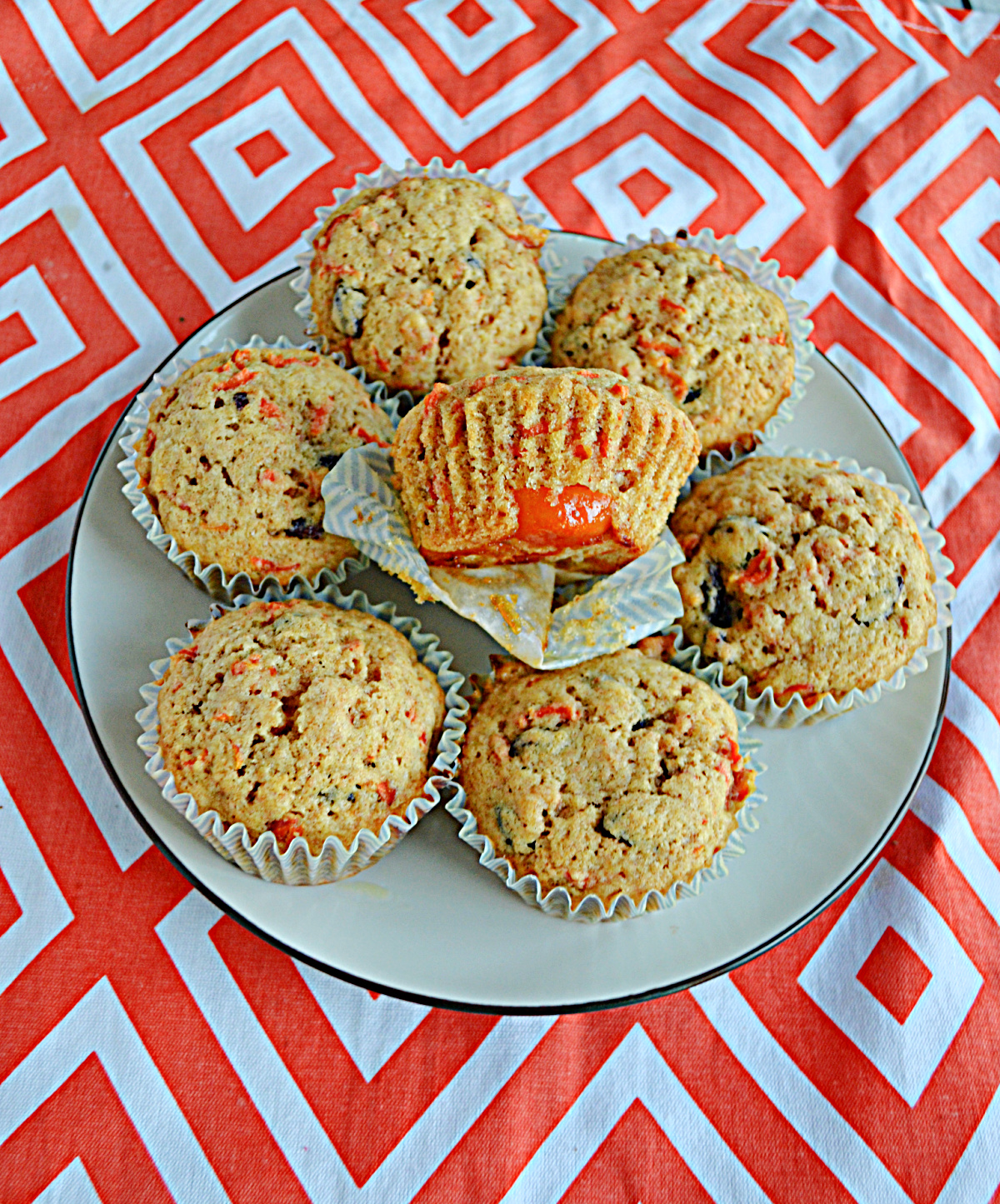 A plate of Kumquat Carrot Cake Muffin with one unwrapped on top.
