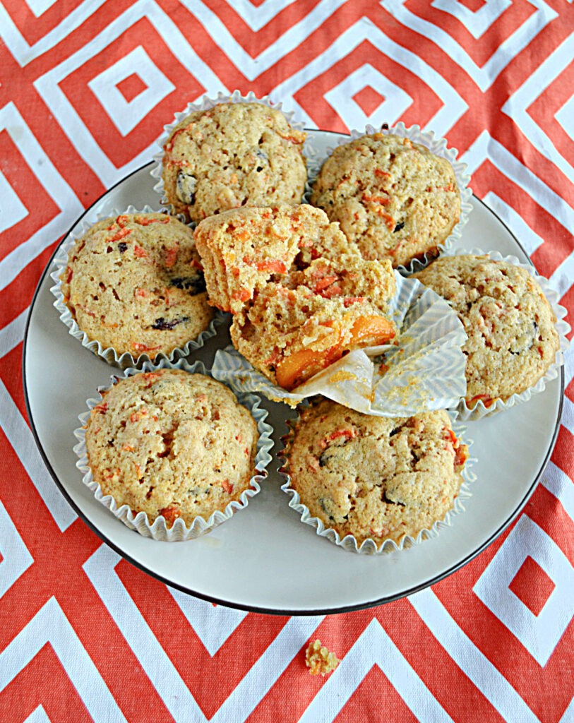 A plate of Carrot Cake Muffins with one broken in half to show the kumquats on the bottom. 