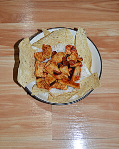 A bowl of chicken and rice with tortilla chips around the bowl.