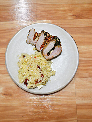A plate with a scoop of couscous and three slices of stuffed pork tenderloin.
