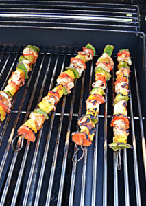Four chicken, bell pepper, and pineapple kabobs on the grill.