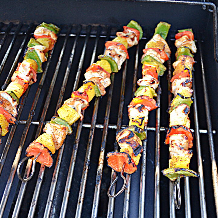 Four chicken, bell pepper, and pineapple kabobs on the grill.
