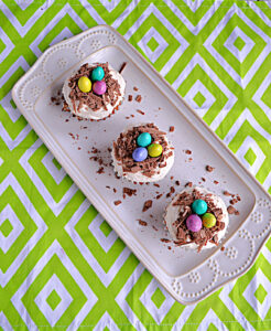 A white platter topped with three cupcakes with chocolate bird's nests and chocolate eggs on top.