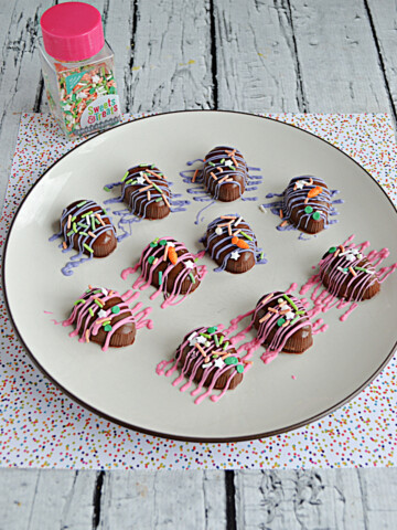 A plate with chocolate coconut Easter eggs on it drizzle in pink and purple chocolate and colored sprinkles.
