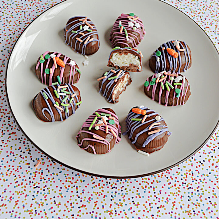 A plate with chocolate coconut Easter eggs on it drizzle in pink and purple chocolate and colored sprinkles and one egg broken open in the middle to show the coconut inside.
