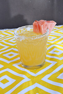 A glass of pineapple cocktail with a pink pineapple garnish.
