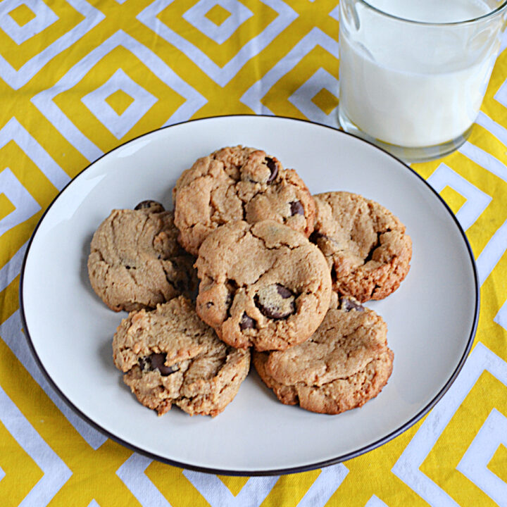 A plate piled with cookies and a glass of milk.