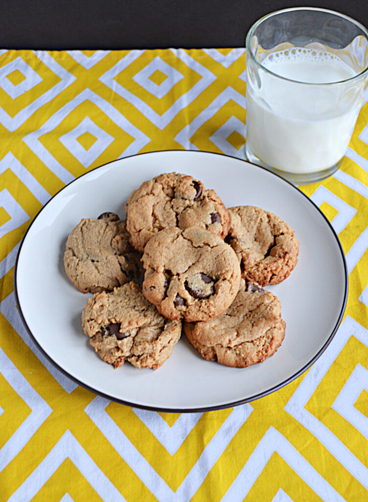 A plate piled with cookies and a glass of milk.