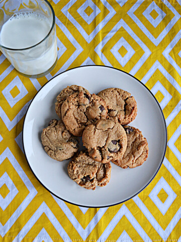 A top view of a plate of cookies and a glass of milk.