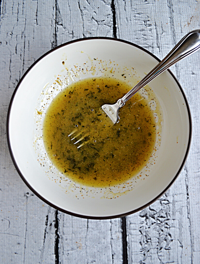 A bowl of honey lime dressing with a fork in it. 