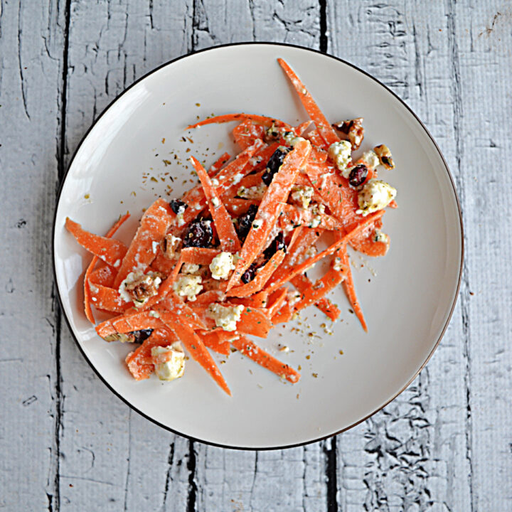 A plate filled with shredded carrots, craberries, and feta.